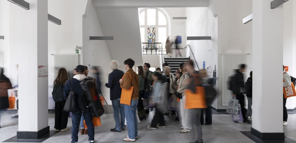 Hallway inside the Dechanatstraße building, HfK Bremen's Music Department, with students gathered and walking around.